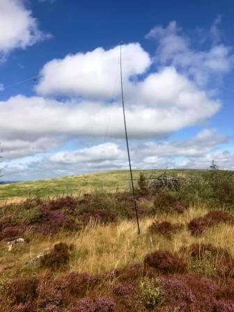 SOTA Pole supporting the HF antenna, with the true summit in the private field behind