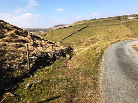 Ignore the first path on the left, bear right on the road, and then left down the slope