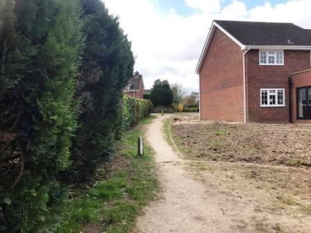 Continue between the hedge and the house