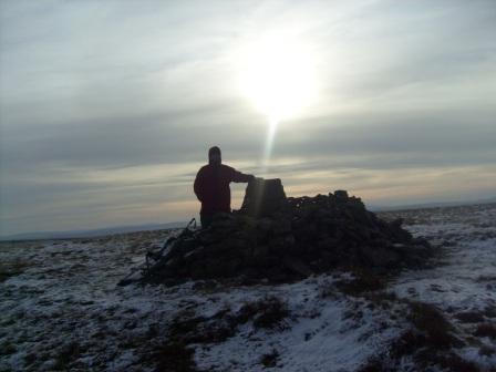 Tom at the summit, under a shaft of sunlight